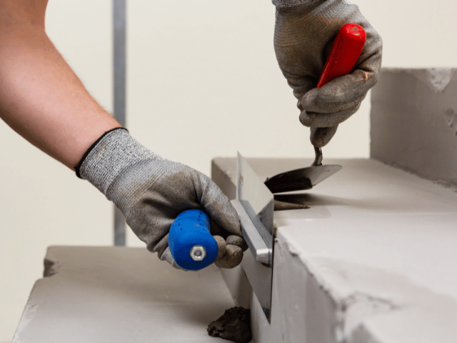 Bostik repair mortar being applied with a trowel to smooth and level a concrete step edge during surface restoration.