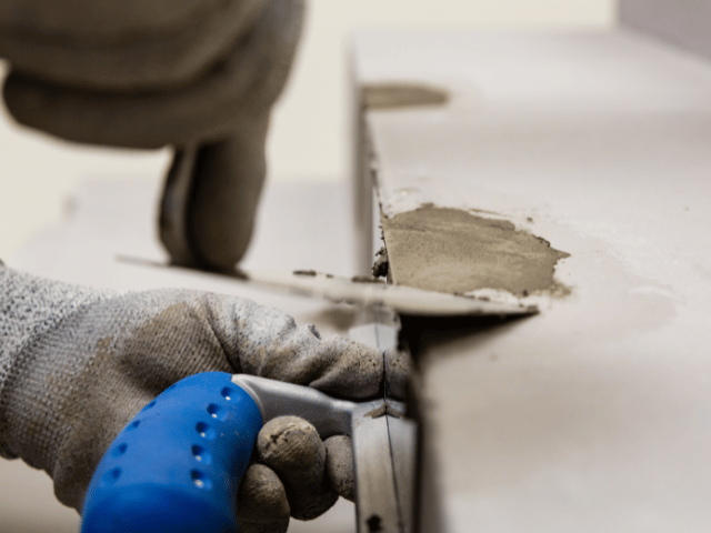 Bostik repair mortar being applied with a trowel to fill and smooth a damaged concrete step edge during restoration.
