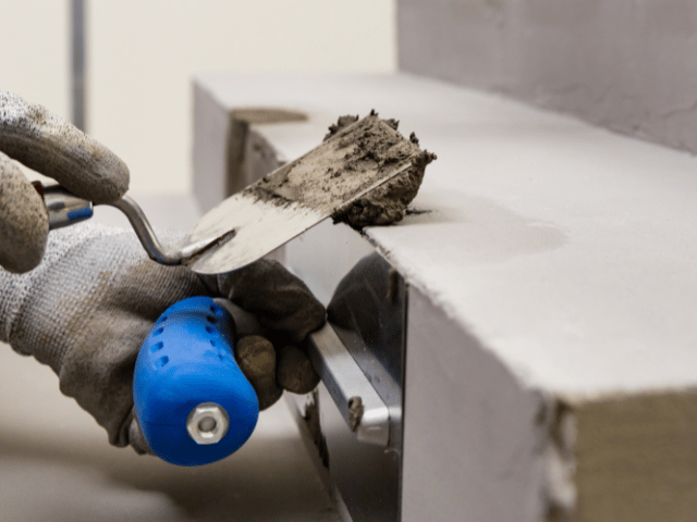 Bostik repair mortar being applied with a trowel to rebuild and smooth the edge of a concrete step during surface restoration work.