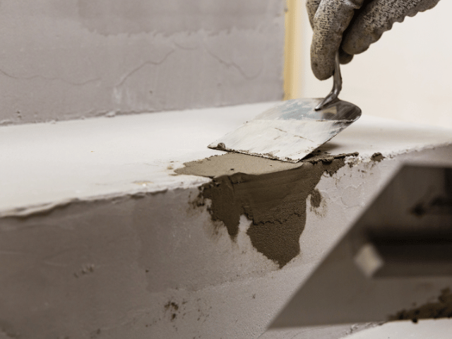man fixing concrete corner with trowel