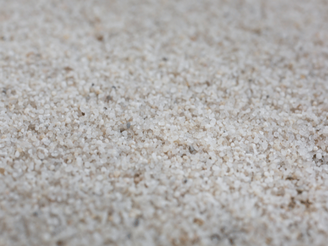 Close-up of Bostik repair sand granules spread across a concrete surface, showing texture used for floor crack preparation and bonding.