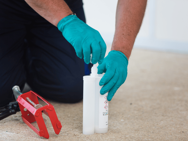 Bostik resin components being mixed in a dual cartridge before application with a professional cartridge gun on a concrete floor.
