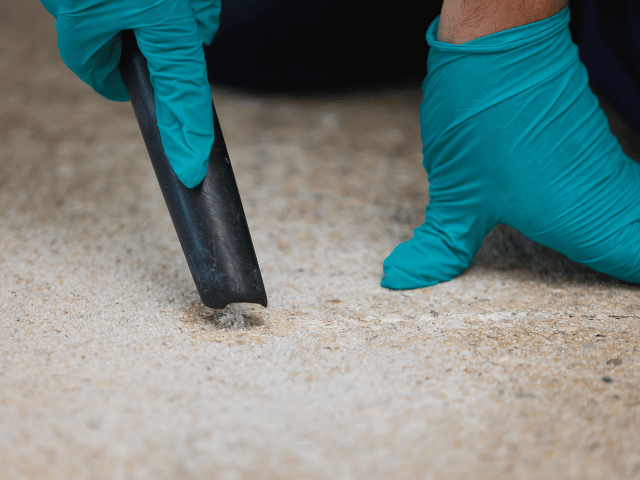 Close-up of a vacuum nozzle removing dust and debris from a drilled hole in a concrete floor before Bostik repair application.