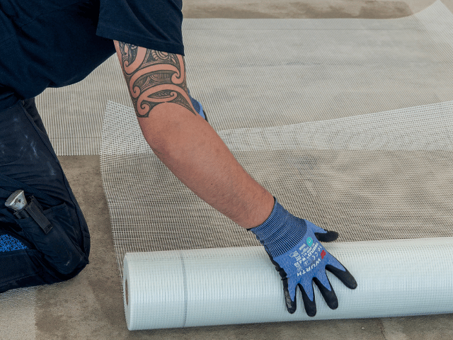 Bostik reinforcement mesh being rolled out across a prepared subfloor surface as part of the Reno U550 floor preparation system.