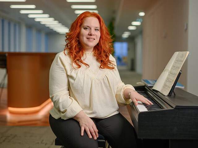 Cecilia sitting at a piano with one hand on the piano keys