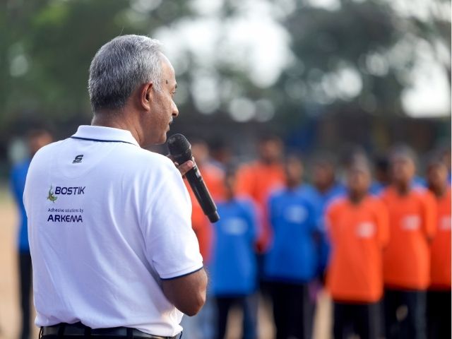 A Bostik representative addressing a group of participants during a community event held outdoors.